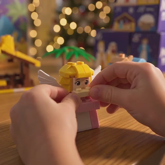 Le mani di un bambino costruiscono l'angelo e lo aggiungono al presepe
